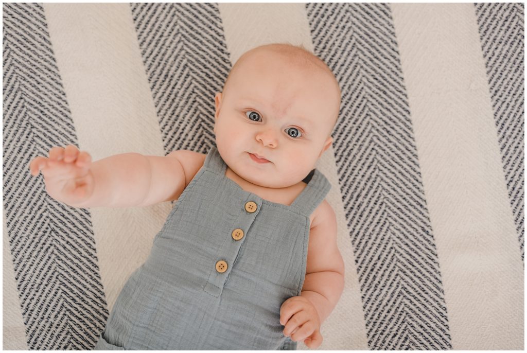 6-month-old lying on chevron striped blanket looking up at camera